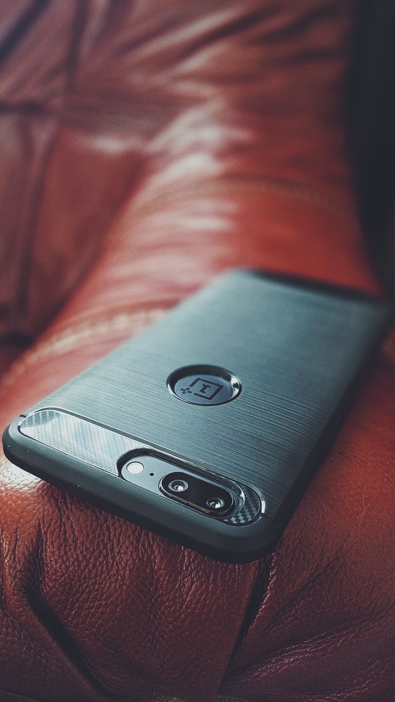 a smartphone sitting on the arm of a leather couch, _smartphone on couch 4k