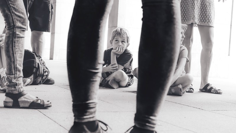 black and white through persons legs shot of child sitting in berlin, berlin child through legs 4k