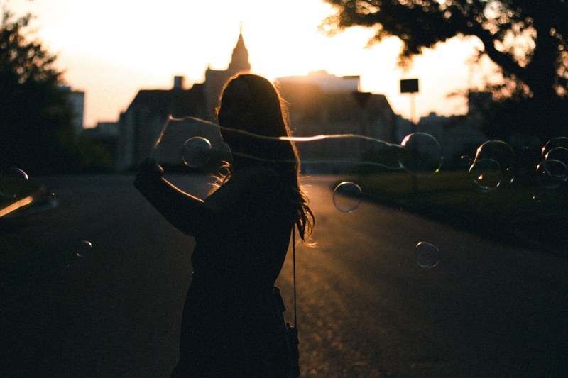 a woman making large bubbles while walking down the street, _silhouette girl making bubbles 4k