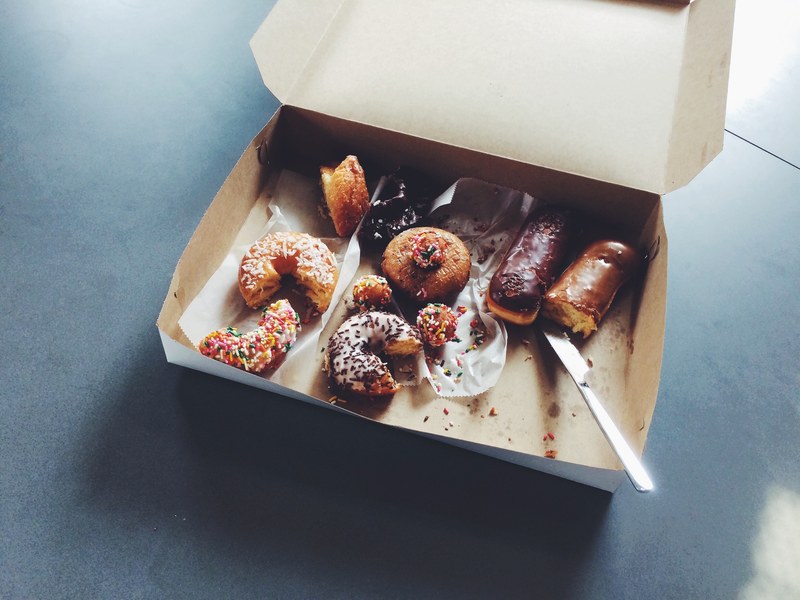 box of half eaten donuts on an office break room table, doughnuts for the office 4k