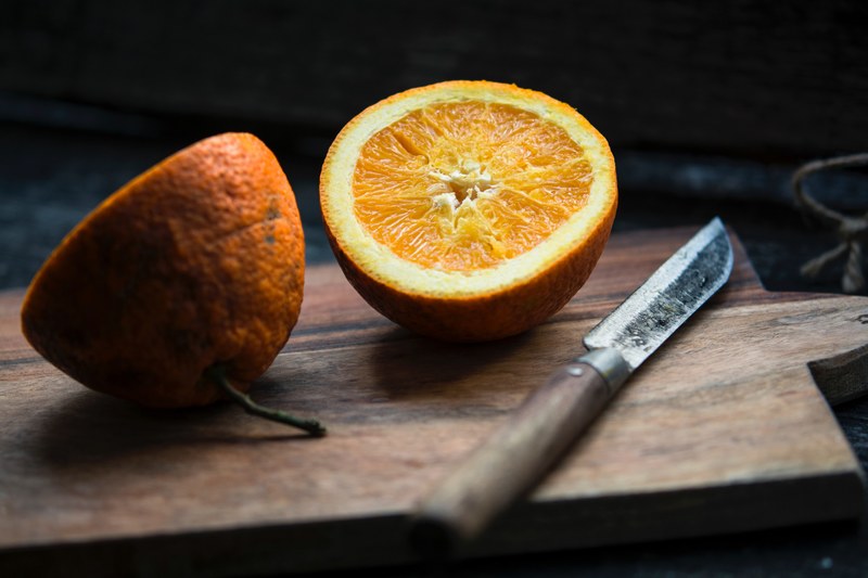 fresh orange slice in half on a rustic cutting board, preparing a healthy snack 4k