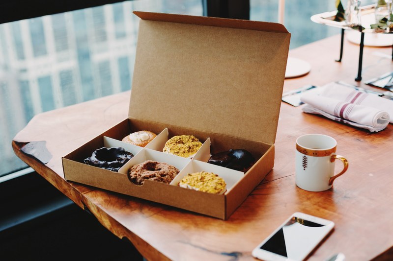 various donuts in a cardboard box on a table, box of happy 4k