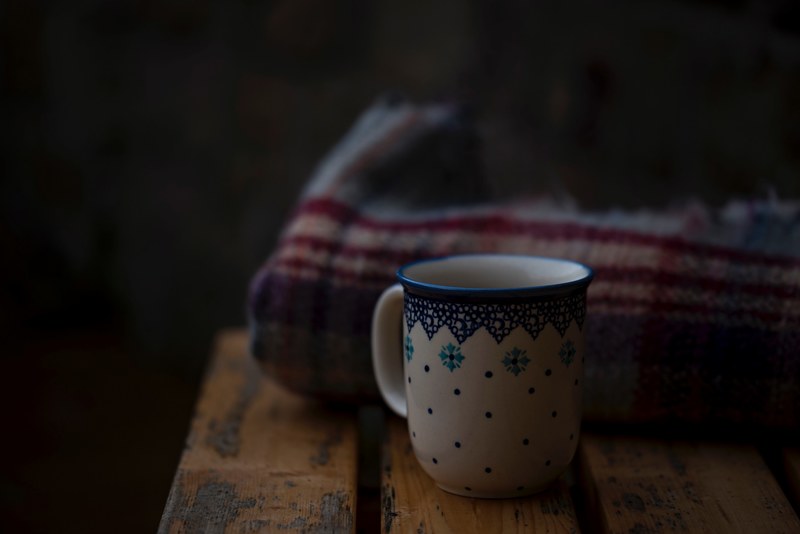 a ceramic mug next to a blanket on a wooden bench, mug and a blanket 4k