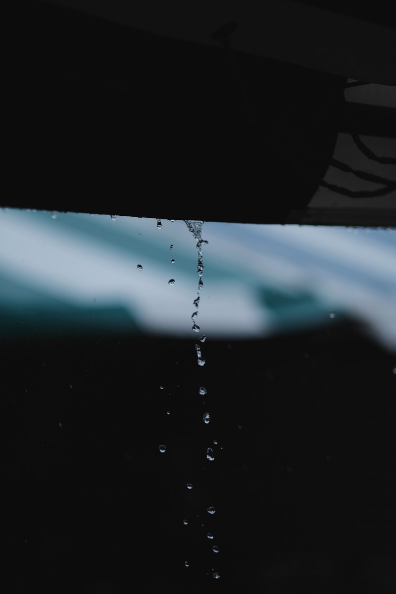macro of trickle of water dropping from a roof in a rainstorm, water falling from roof 4k