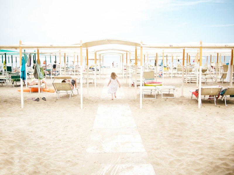a woman running on sand in a walkway on a busy beach, woman running on beach 4k