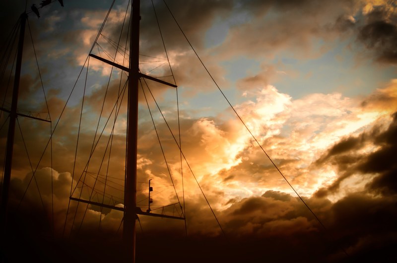 a ships mast with rigging is set against golden clouds during sunset at la paz, la paz boat sunset_ 4k