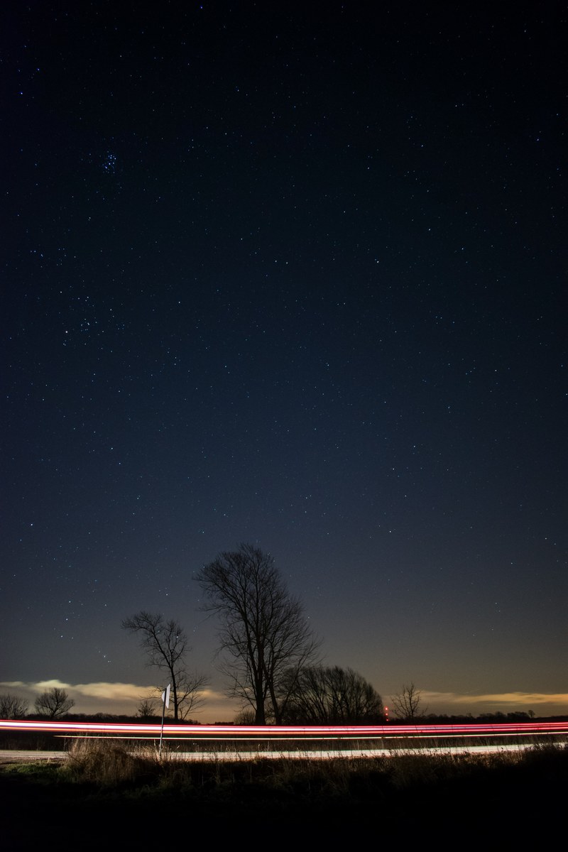 a light rail image with a dark night sky and tree silhouettes in the horizon, lost in space 4k
