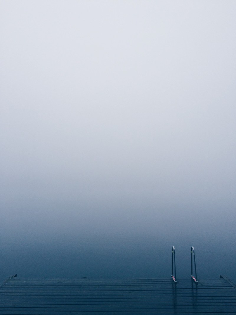 lake pier with a ladder on serene waters on a foggy day, a dock during winter 4k