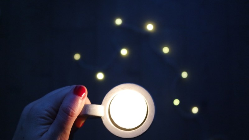 a woman with red fingernail polish holding a cup with a white light in it, _the lights at the end of the day 4k