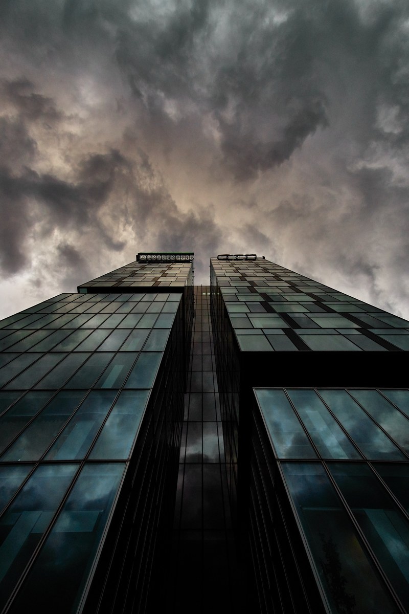 looking up at dark clouds from the base of a modern skyscraper in bucharest, _clouds skyscraper bucharest 4k