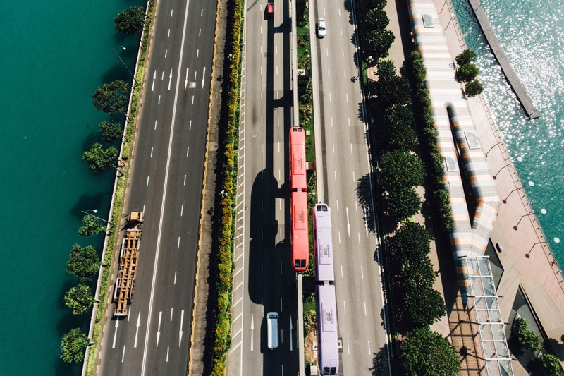 a drone shot of urban trains in the middle of a freeway in singapore, singapore freeway 4k