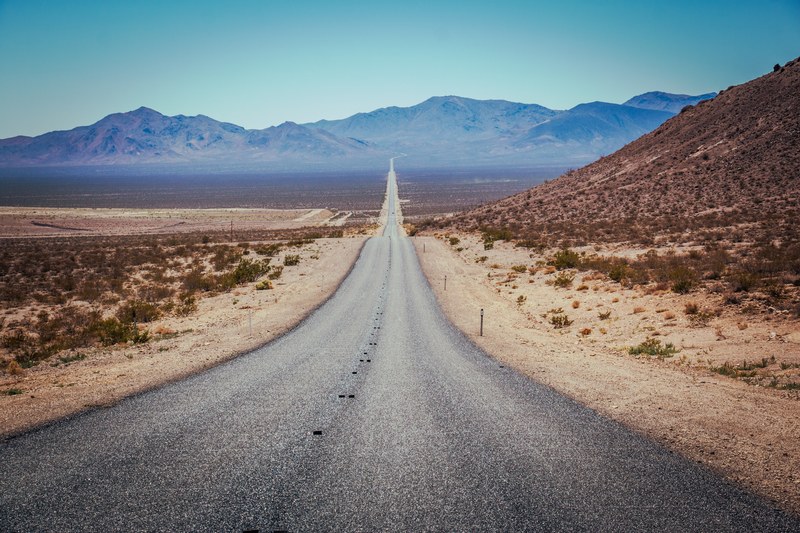 rural road leads through desert brush to the mountains, highway up to horizon 4k