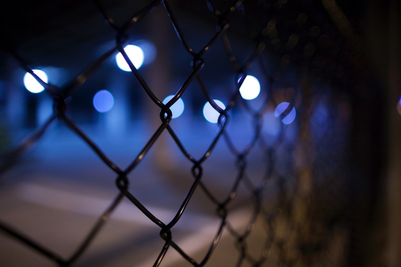 a chain link fence blocking several dots of blue and white light, chain link fence 4k