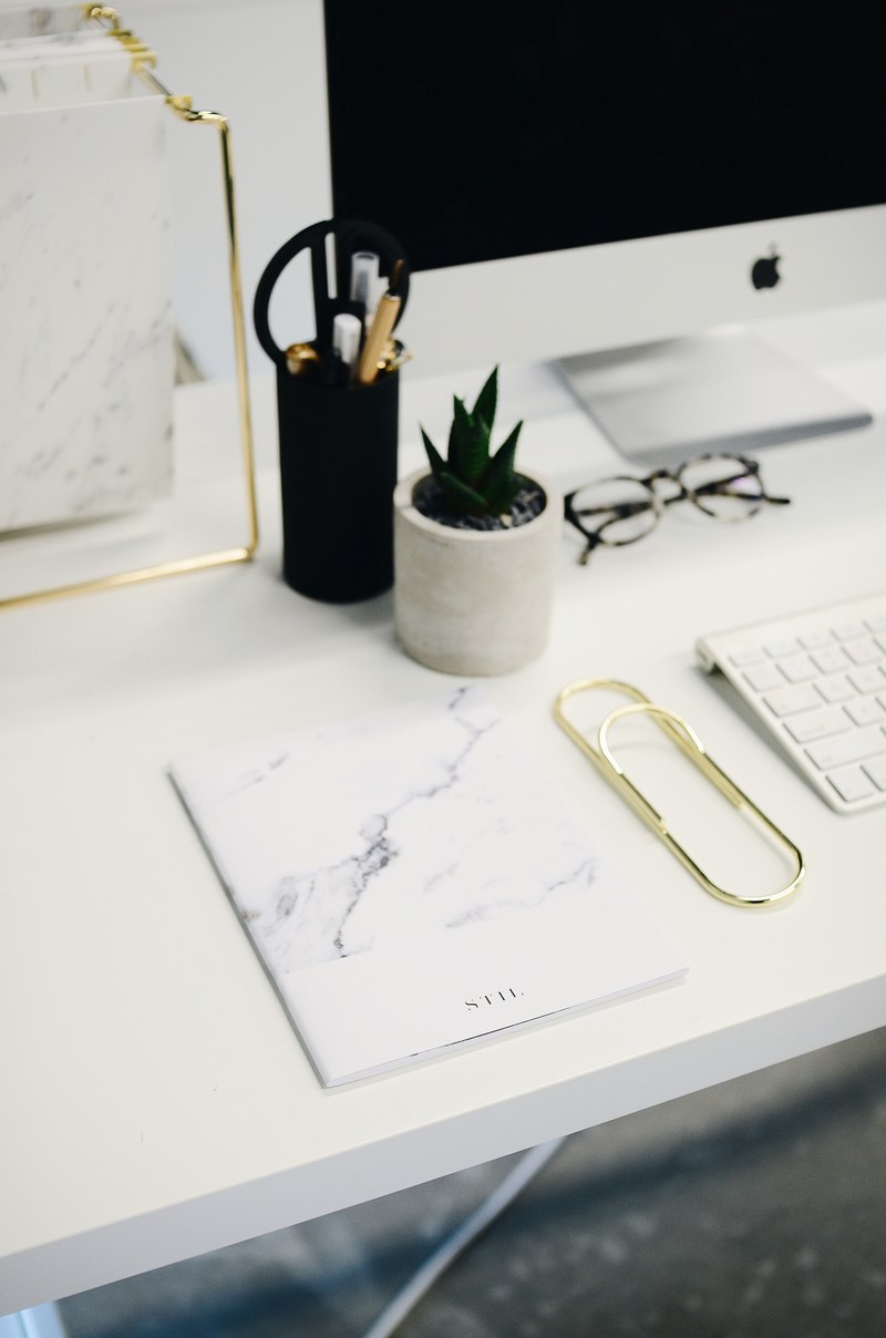a book and a large paper clip on a computer desk with an imac, a marble journal 4k