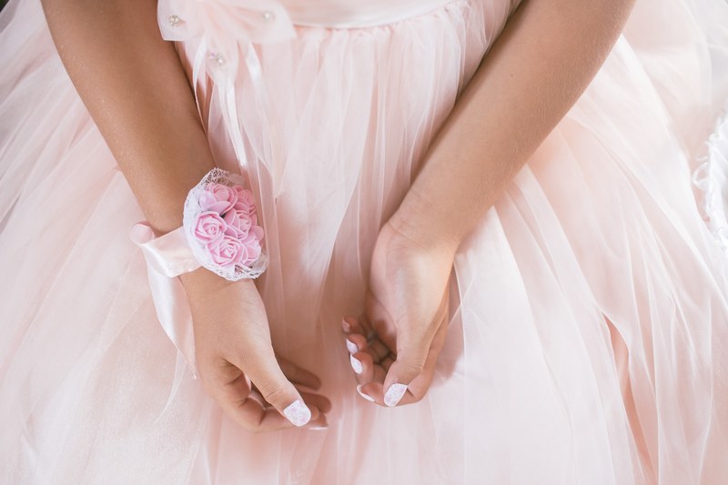 close up of the hands of a little girl in a dress with a pink wrist corsage, girl with a wrist corsage 4k