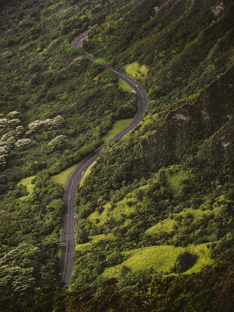 a winding road among green wooded hills in hawaii, winding around 4k