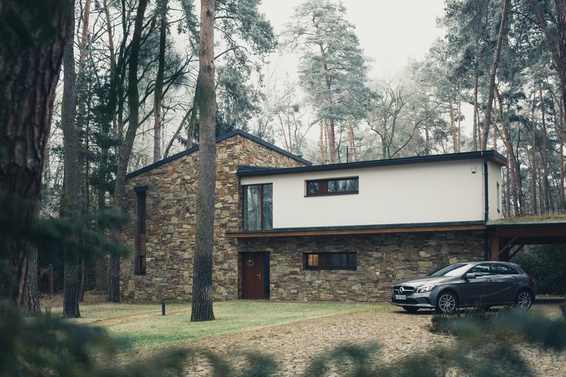 modern brown and white house in the middle of pine tree forest with car parked in driveway, house in forest 4k