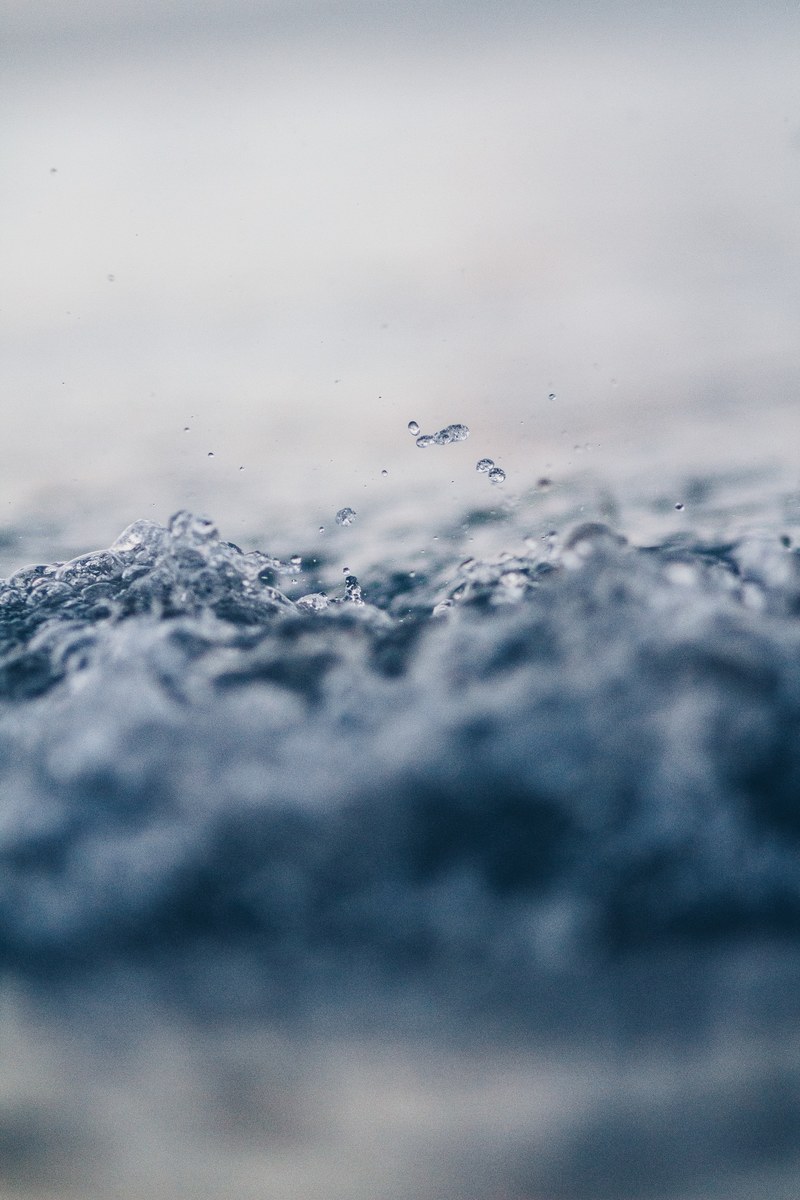 close up of splashing water with tiny droplets above, one drop in the ocean 4k