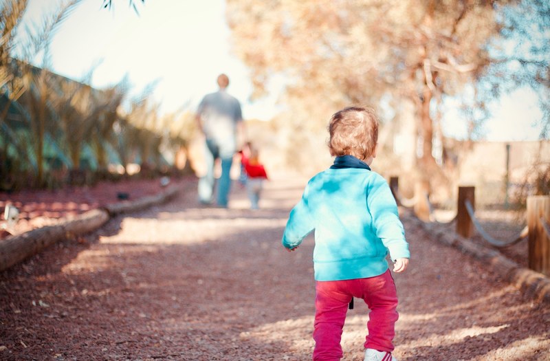 a child walking along a park path to catch up with their family, walking to the playground 4k