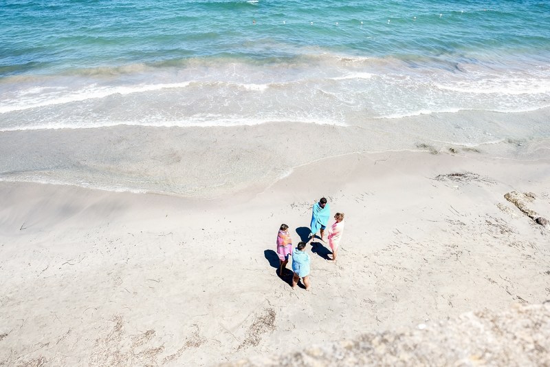 a high angle shot of a group of people wrapped in towels on a beach, drying off after a swim 4k