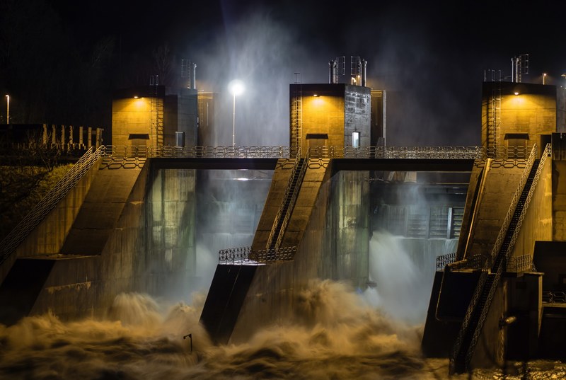 industrial hydroplant buildings with rushing water on a dark stormy night, stormy night at the dam 4k