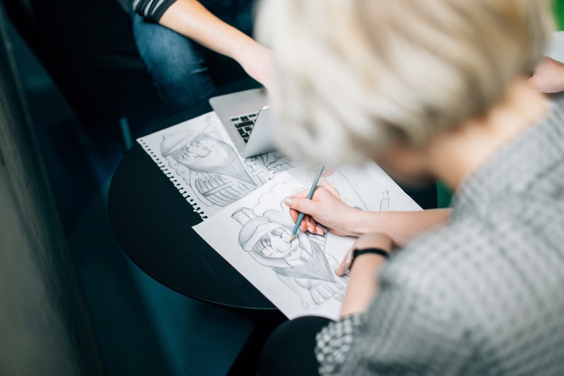 a caucasian female drawing and sketching a character with her pencil, female sketching on paper 4k