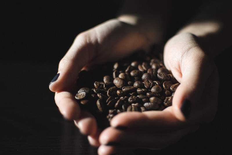 a womans hands with fingernails painted black holding dark brown coffee beans, girl holding roasted coffee beans 4k