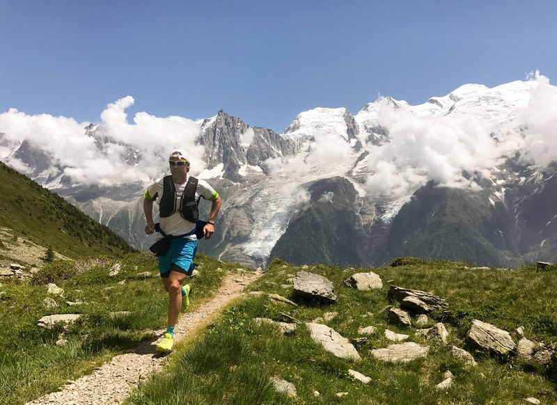 a man jogging on a narrow footpath in high mountains, trail running in chamonix 4k