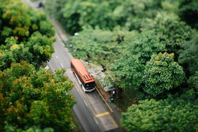 a drone shot of a bus at a stop on a tree lined road, bus at a stop from above 4k