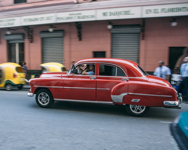 a shiny red vintage car drives through the streets of la habana cuba, vintage havanna 4k