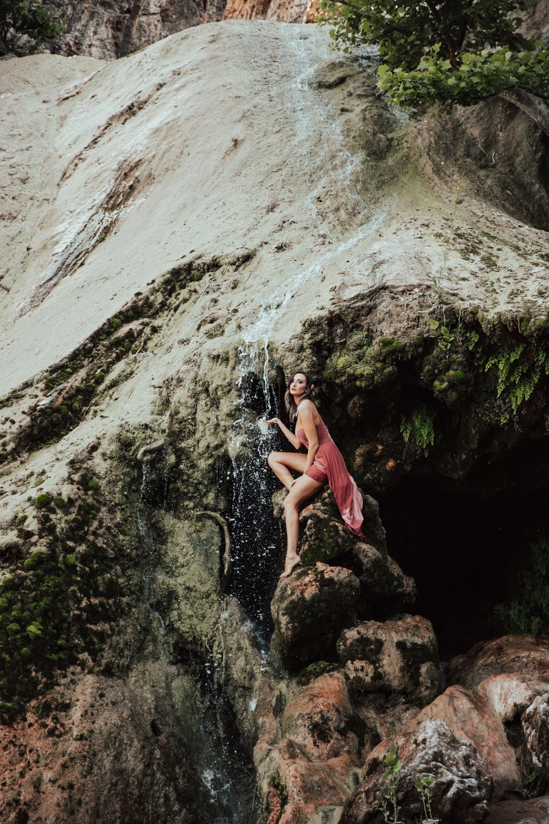 woman posed like a water nymph near waterfall in a natural landscape, secluded waterfall 4k