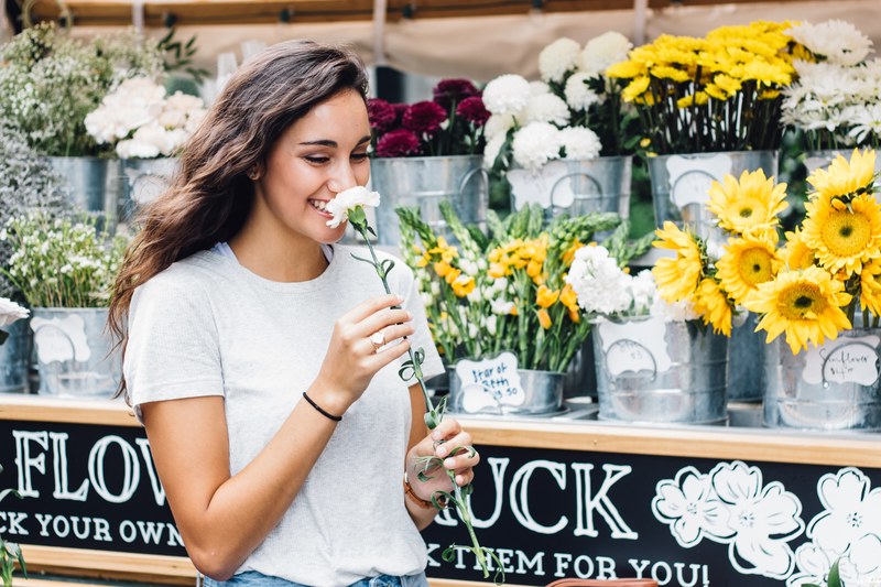 a woman at a floral stand in nashville smiles while smelling a white flower, woman smelling a flower 4k