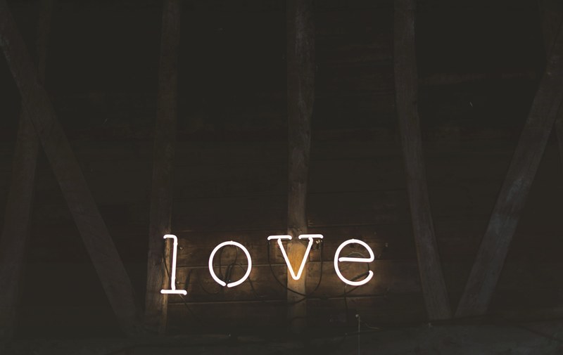 neon lights spell out love against a wooden barn wall, neon love sign 4k
