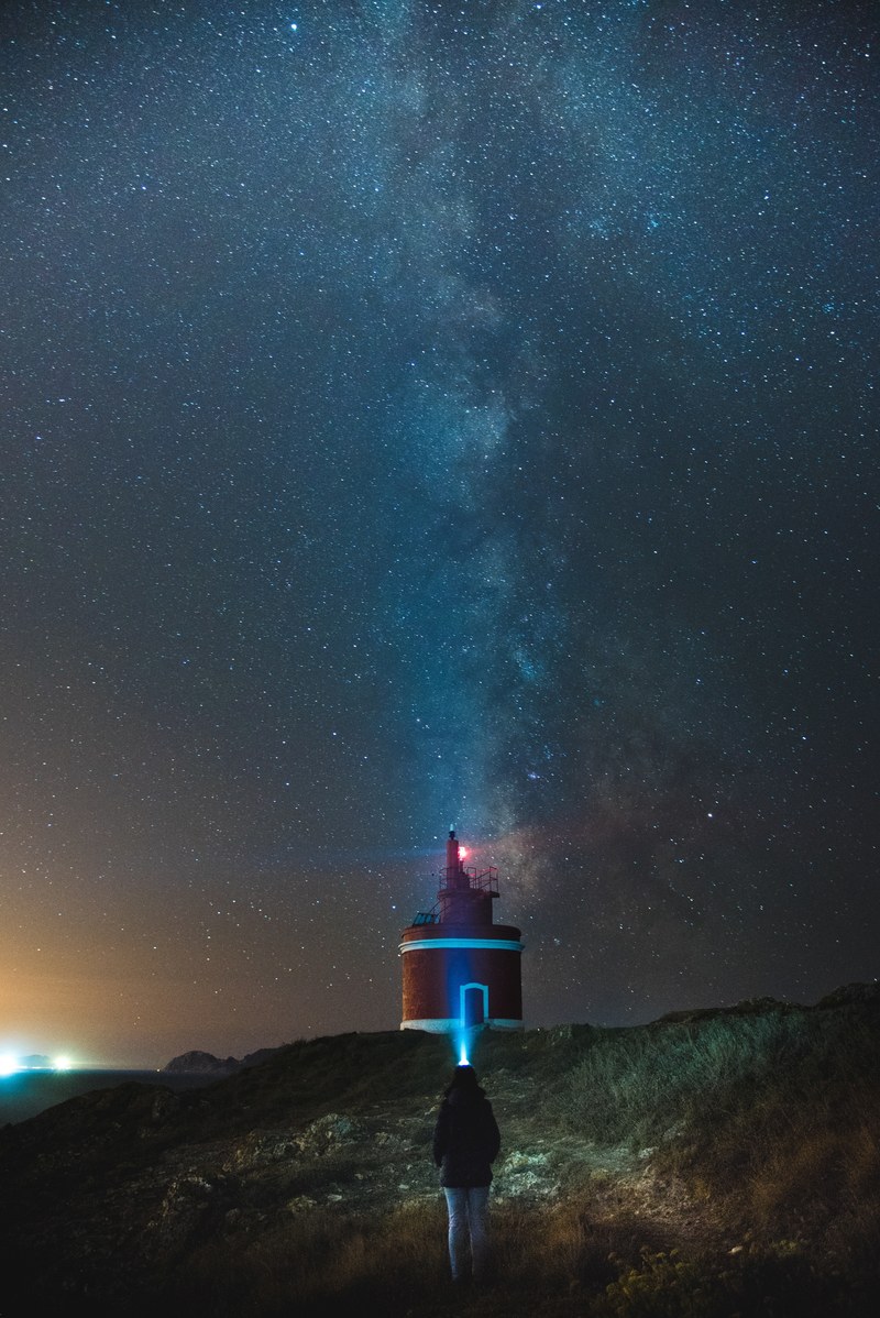 a blue starry sky above a lighthouse, _milky way over punta robaleira lighthouse 4k
