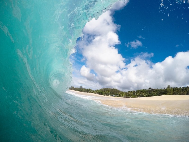 a large bright blue wave coming in near a beach, _large beach wave 4k