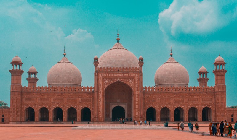 tourists explore the ornate badshahi mosque on a bright blue day, the badshahi mosque 4k