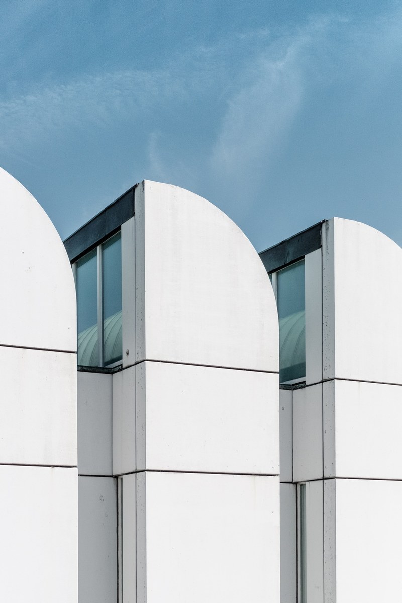 a white three partite building facade under a blue sky, white bauhaus architecture 4k