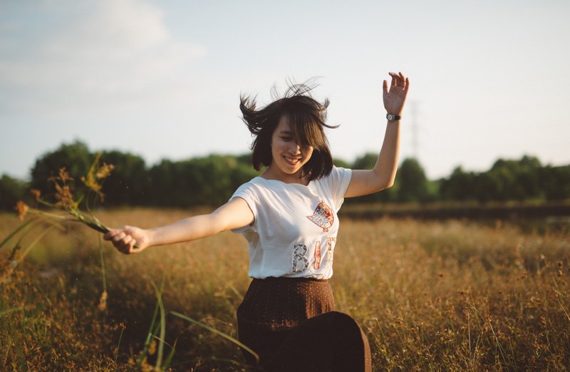 happy caucasian girl with grass in hand dancing to the tunes of summer, girl dancing happily 4k
