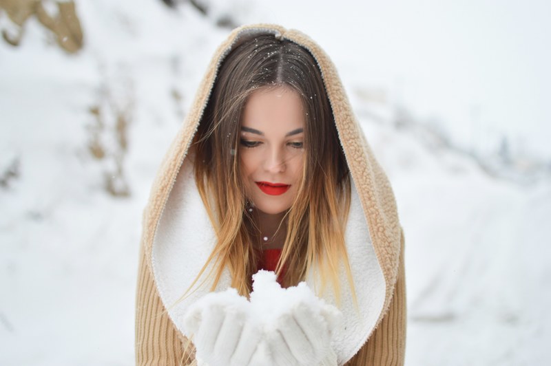 a smiling woman in a hooded coat and gloves holds a handful of snow in florina, handful of snow 4k