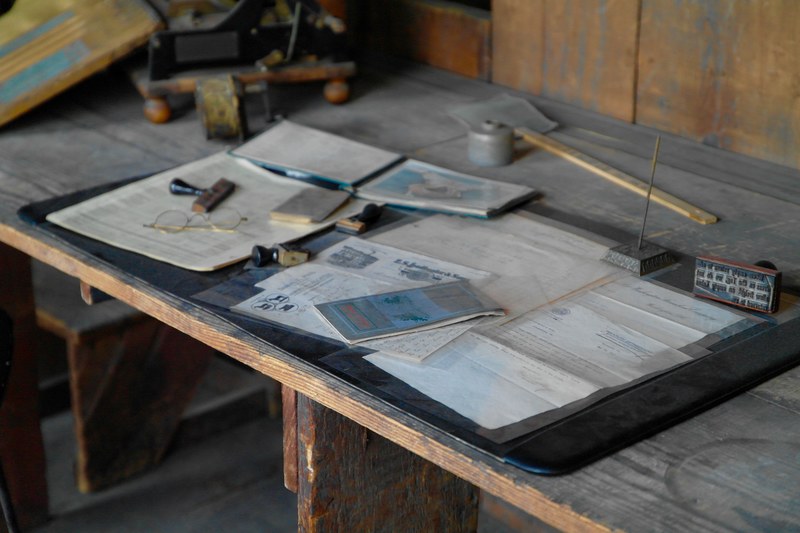 documents and maps on a messy workbench, glasses paper on wood table 4k