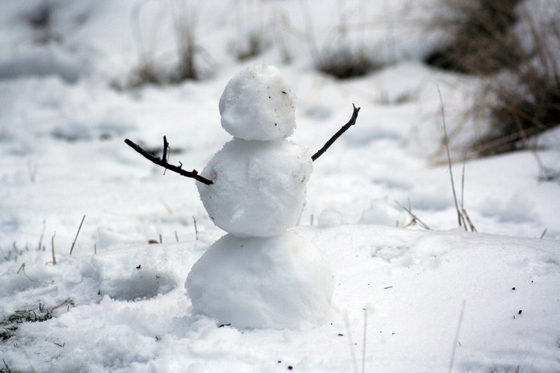 three small balls of snow sit on top of each other while twigs stick out on either side to make a faceless snowman, faceless snowman 4k