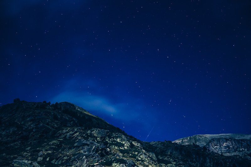 dark blue sky speckled with stars over jagged mountain slopes, starry sky over rough mountains 4k
