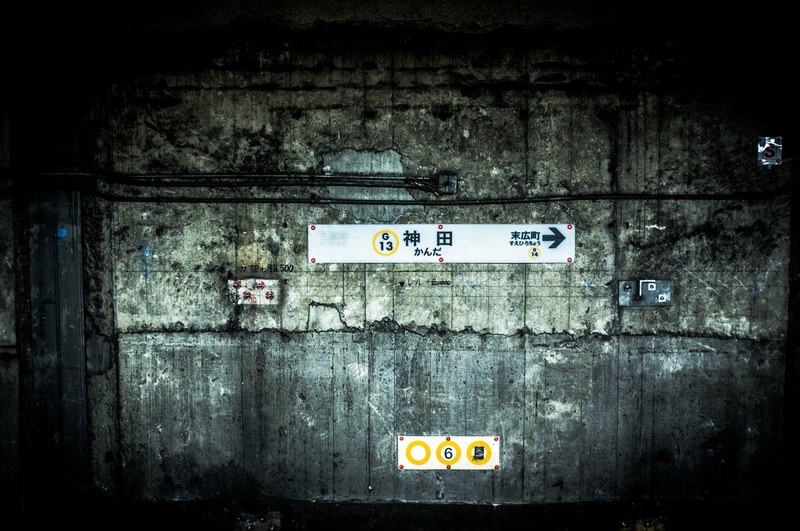 white signs showing the direction on a worn out wall at a railway station, kanda tokyo metro subway station 4k
