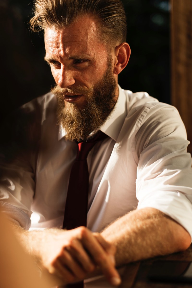 a bearded man in a white shirt and a red tie talking at a table, elegant bearded man at a table 4k