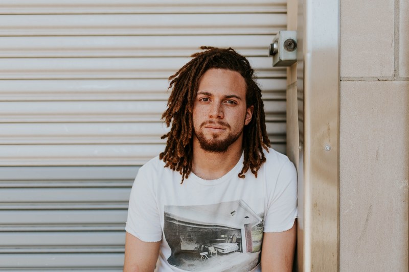 happy man with dreadlocks and a beard smiles outside, sitting and smiling 4k