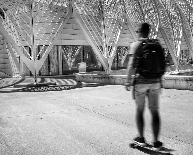 blurry shot of a skateboarder riding through an empty plaza, polytech student 4k