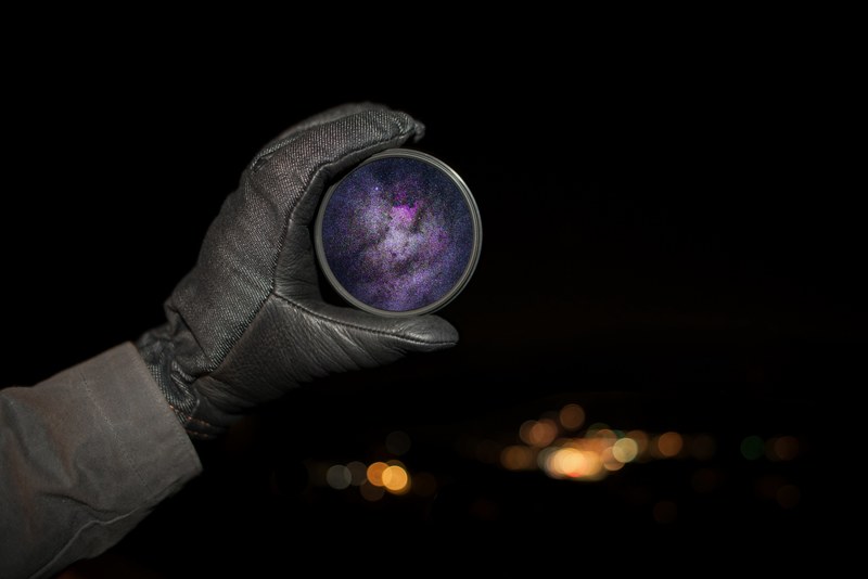 a person holding a lens filter with the galaxy and stars on it in silverthorne, silverthorne night photography 4k