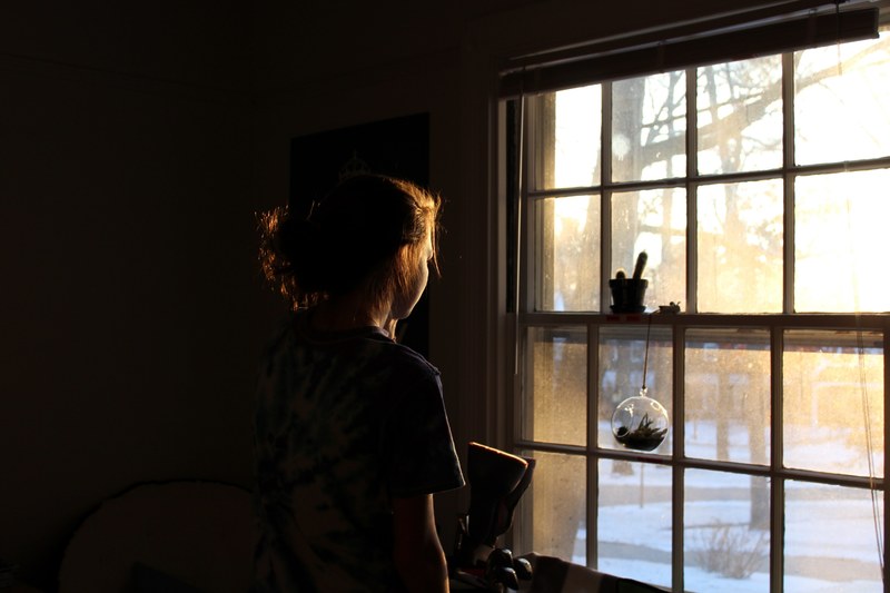 a womans dark silhouette looks out the window into the brightness of the day, _a woman looking out the window 4k