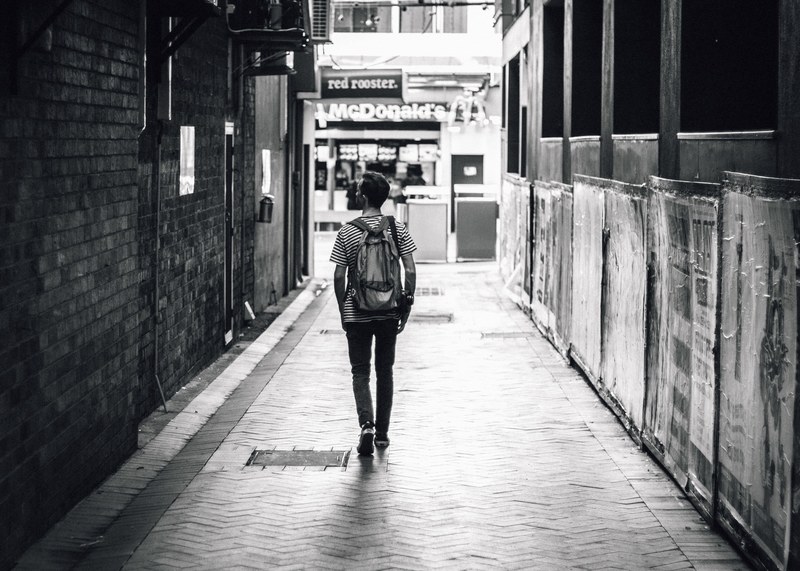 man walking down an open alley in a striped shirt with a mcdonalds ahead of him, alleway in brisbane 4k
