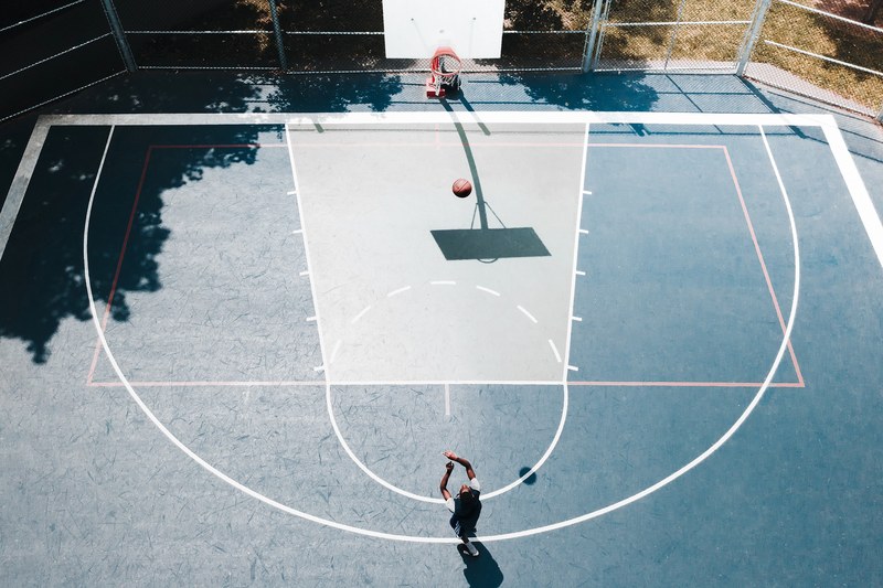 drone view of person shooting basketball into hoop on a court outdoors, three points_ 4k